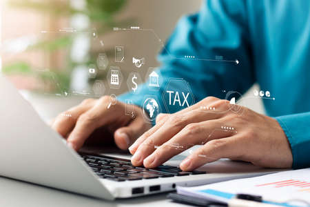 Businessman using his laptop computer to fill out online personal income tax return form for tax payment, personal income tax calculation.の写真素材