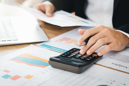 Investors are calculating profits and costs with calculators, growth and investment chart analysis,...