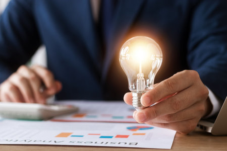 Innovation through ideas and inspiration ideas. Human hand holding light bulb to illuminate, idea of creativity and inspiration concept of sustainable business development.の写真素材