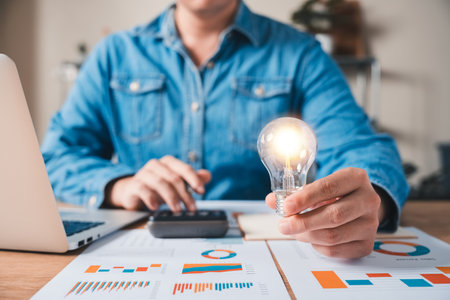 Innovation through ideas and inspiration ideas. Human hand holding light bulb to illuminate, idea of creativity and inspiration concept of sustainable business development.の写真素材