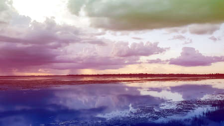 Beautiful sunset landscape with reflection on river sky and clouds in vintage toneの写真素材