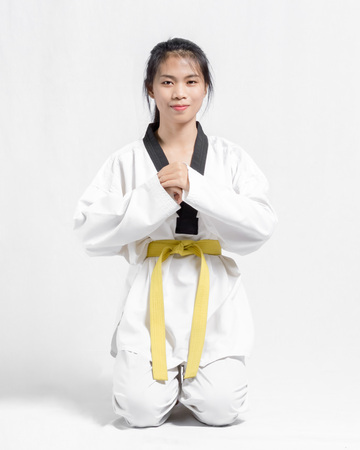 Portrait of a beutiful asian girl with taekwondo yellow belt. Isolated on grey backgroundの写真素材