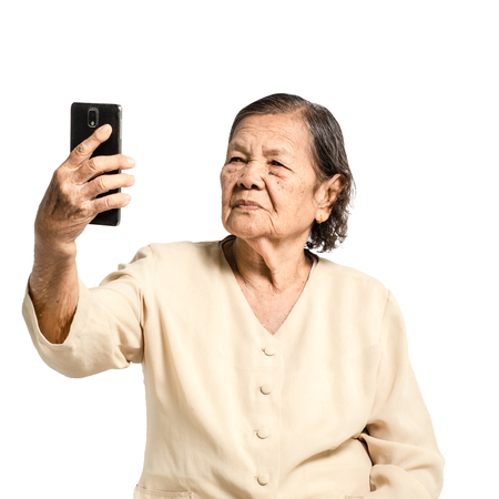 portrait of a senior woman selfie with smart phone. Isolated on white backgroundの写真素材