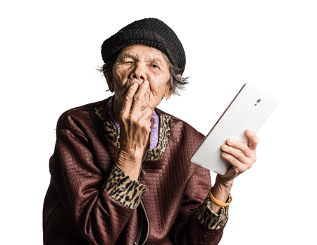 Portrait of a senior woman confused with tablet in vintage costume. Isolated on white backgroundの写真素材