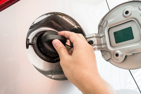 Hand opening the oil filler cap at the gas stationの写真素材