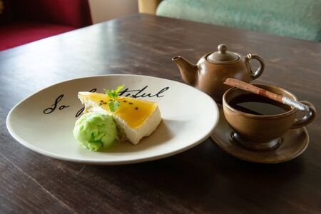 Passion Fruit Cheesecake and lime ice cream Served with a cup of hot aromatic teaの写真素材