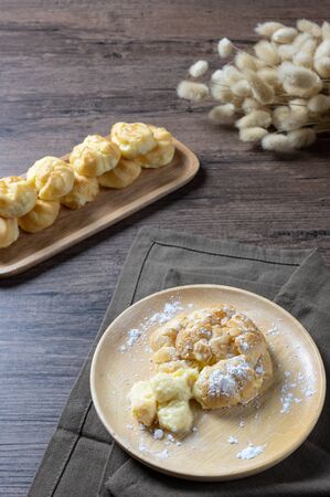 Delicious eclairs or cream puff or French profiteroles or choux dough filled with vanilla custard cream,on wooden background.の写真素材