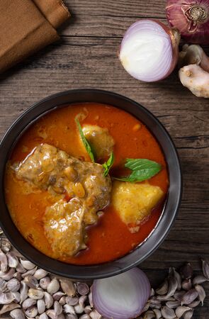 Chicken massaman curry in black bowl with herb and spices on wooden background. Thai authentic food called massaman kai. top view. Flat lay.の写真素材