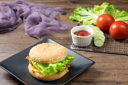 Crispy fried chicken burger on black plate served with french fries and ketchup on wooden background.の写真素材