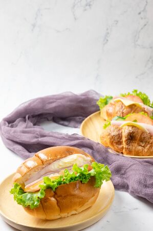 Delicious croissants sandwichs with fresh Ham, cheese, tomato, cucumber, lettuce and Sub sandwich with fresh salad, Ham , cheese served on round wooden plate. white background.の写真素材