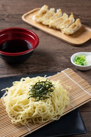 Zaru Ramen, Japanese cold buckwheat noodles served on bamboo colander with seaweed,chopped green onions, grated wasabi,Grated radish and dipping cold soup. served with Gyozas,fried japanese dumplingsの写真素材