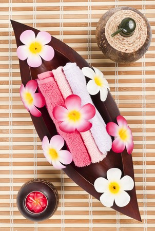 Fresh towels in the wooden leaf tray on the bamboo matの写真素材