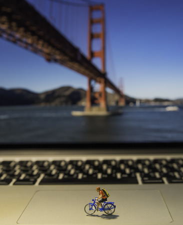 Man riding bicycle model on laptop with Golden Gate bridge backgroundの写真素材
