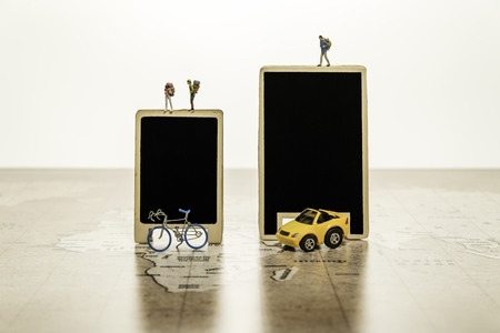 Two blank black boards with tiny human model with car and bicycle on world mapの写真素材