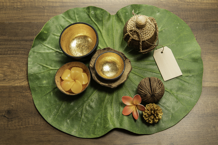 Two golden bowl with flower shape of candle on green leafの写真素材