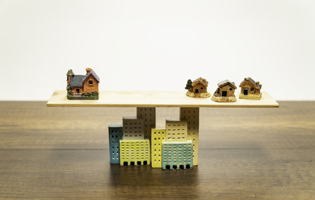 Big orange house balance with three small houses based on buildingsの写真素材