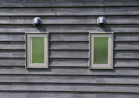 Two small green windows of restroom on wooden wall