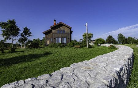 Black wooden house with blue sky and long low fenceの写真素材
