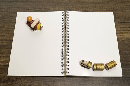 Golden wooden train on blank white notebook and red wooden airplaneの写真素材