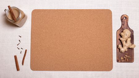 Masala tea with spices and ingredients on light linen with cork board. Copy space