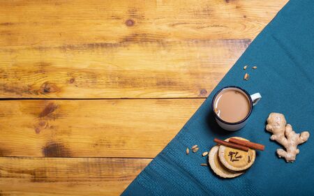Metal mug with masala tea with spices and ingredients on wood table with blue cloth. Horizontal...