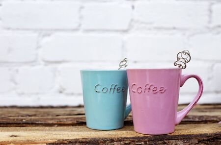 Colorful pink and blue cups for romantic couple on wooden table against white brick wall for valentine s day card.の写真素材