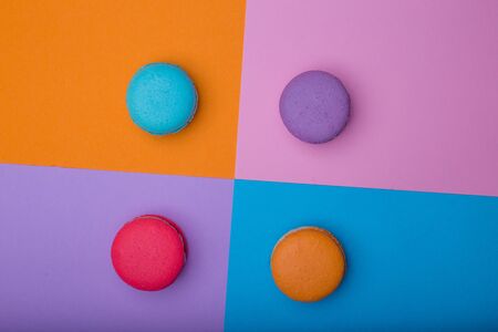 Sweet colorful macaroons on multicolored square background