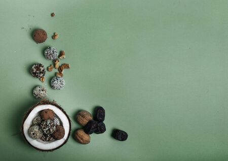 Raw protein energy balls with nuts, dried fruits and honey in the half of coconut with flower petals...