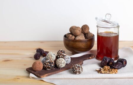 Raw protein energy balls with nuts, dried fruits and honey on wooden desk with ingredients and light...