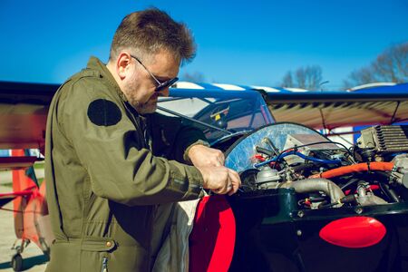 Pilot repairs small aircraft. Man in flight suit