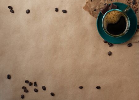 Dark green cup of espresso with coffee beans on brown craft paper background. Top view, copy space, horizontalの写真素材