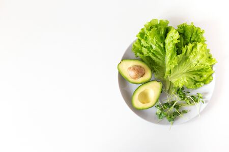 Vegan detox plate with green vegetables. Raw avocado, salad, micro greens on white background. Top view, copy spaceの写真素材