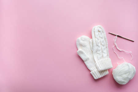 Christmas mittens made from white knitted thread on pink backgroundの写真素材