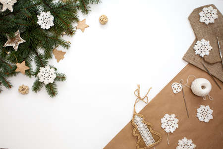 Preparing for Christmas flat lay. Christmas crafts. Knitting snowflakes by white yarn. Tree branches with DIY zero waste decorations on white background. Reusable sustainable recycled handmade decorの写真素材