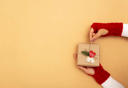 Hands in knitted red gloves holding a gift and pulling the string on it. Zero waste Christmas...