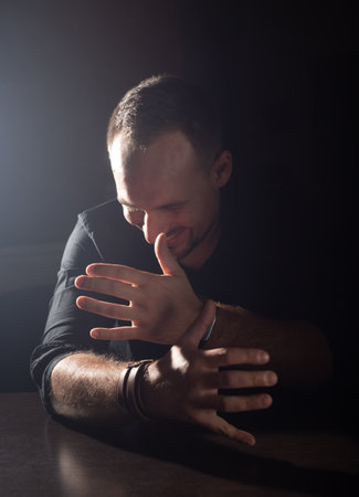 Close up portrait of laughing attractive middle aged man with hand gesture on dark background with...