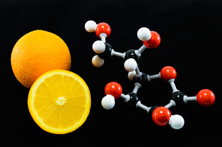 Orange and vitamin C structure model (Ascorbic acid) on black background for education