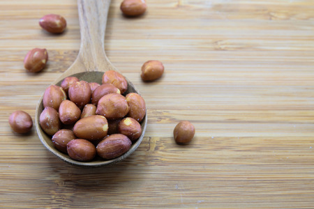 Close up of skin red peanuts in spoon on wood backgroundの写真素材