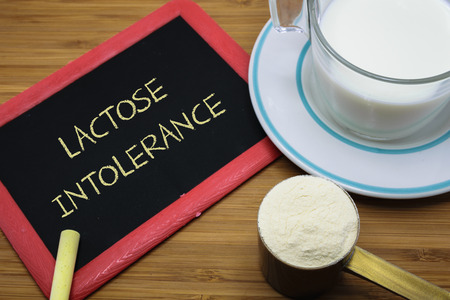 Lactose intolerance word on chalk board with a cup of milk and  milk powderの写真素材
