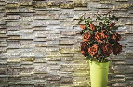 Red rose bouquet in green bucket with stone wall background in vintage styleの写真素材