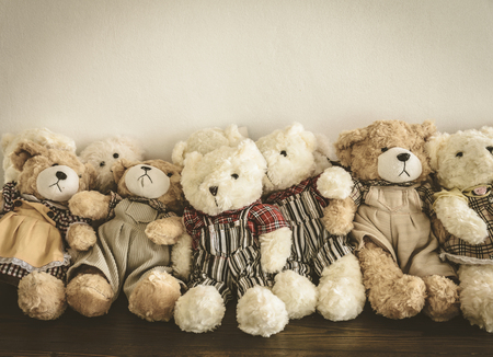 A group of cute teddy bears sitting together on wooden desk in vintage styleの写真素材