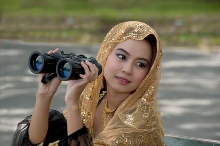Pretty Asian woman in black Indian clothes with binocular の写真素材
