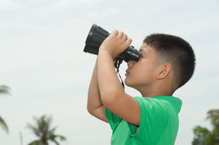 Little boy looking through the binocular 