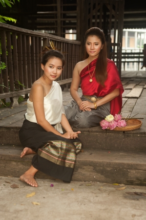 Pretty woman in Thai style clothes in posing artificial flowers  の写真素材