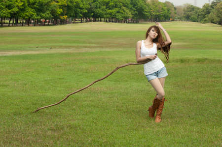 Pretty Asian woman in posing with long branches on the lawn  の写真素材