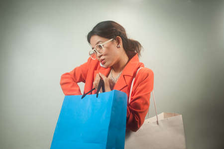 Busy young Asian business woman with shopping bags on a  background  の写真素材