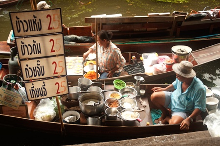 Ratchaburi, Thailand - July 21, 2013   Senior Thai woman and male selling noodle freshly cooked food on her boat in Damnuan Saduak Floating Market,Ratchaburi Province in Middle of Thailand のeditorial素材