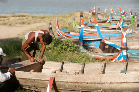 Man repair traditional boat on the shore of the Taungthaman lake near U-Bein Bridge.のeditorial素材