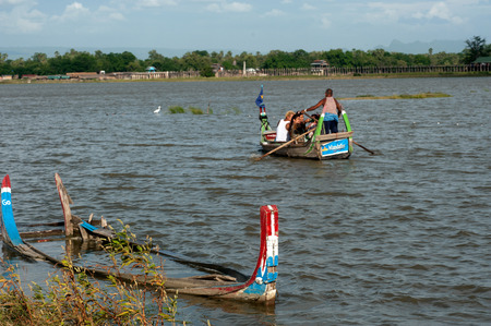 Man paddle and tourist sitting at traditional boat on the Taungthaman lake near U-Bein Bridge.のeditorial素材