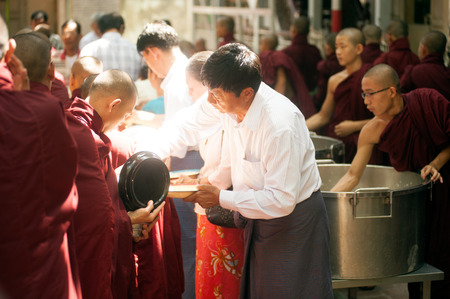 Peoples giving with alms to a Buddhist Monk in Myanmar.のeditorial素材